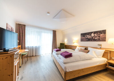 Superior Zimmer mit Doppelbett, Parkettboden, Fenster und rotem Teppich.