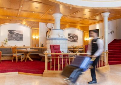 Hotellobby mit rotem Teppich, Sitzmöbeln und Mitarbeiter mit Gepäck.
