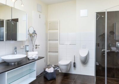 Modernes Badezimmer mit bodengleicher Dusche, WC und Urinal.