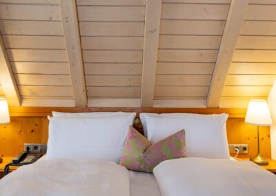 Schlafzimmer unter dem Dach mit Doppelbett, Kissen und Holzdecke.