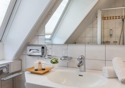 Badezimmer unter dem Dach mit Badewanne, Waschbecken und Fenster.