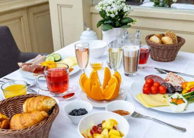 Frühstückstisch mit Obst, Croissants, Joghurt und Fruchtsäften.