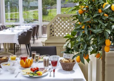 Restauranttisch mit weißer Tischdecke, Gedeck und bunten Frühstücksspeisen.