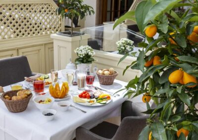 Restauranttisch mit weißer Tischdecke, Gedeck und bunten Frühstücksspeisen.