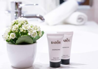 Nahaufnahme von Babor Pflegeprodukten, weißem Handtuch und Blumendekoration.