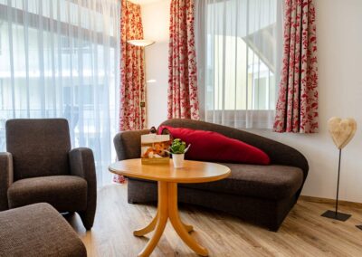 Wohnbereich mit Sofa, Couchtisch und zwei Sesseln am Fenster.
