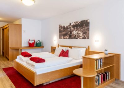 Hotelzimmer mit Doppelbett, rotem Teppich und Holzdetails.