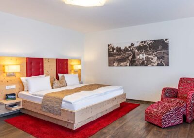 Hotelzimmer mit Doppelbett, rotem Teppich und Fototapete.