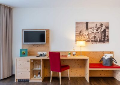 Arbeitsbereich mit Schreibtisch, Wand-TV und Landschaftsbild.