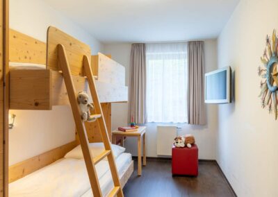 Hotelzimmer mit zwei Etagenbetten, Stofftieren und Tageslicht.