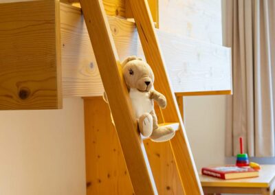 Detailaufnahme eines Holzhochbetts mit Stofftier auf der Leiter.