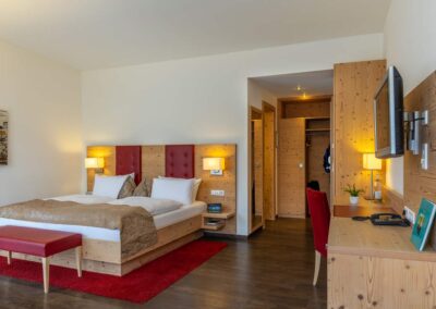 Hotelzimmer mit Doppelbett, rotem Teppich und Leselampe.